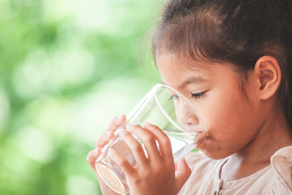 Young girl drinking a glass of water. 